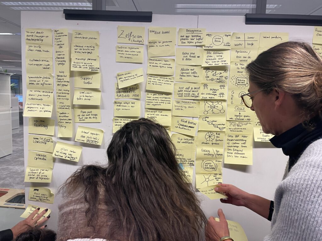 Deelnemers plakken post-its op de muur tijdens Double Diamond-sessie